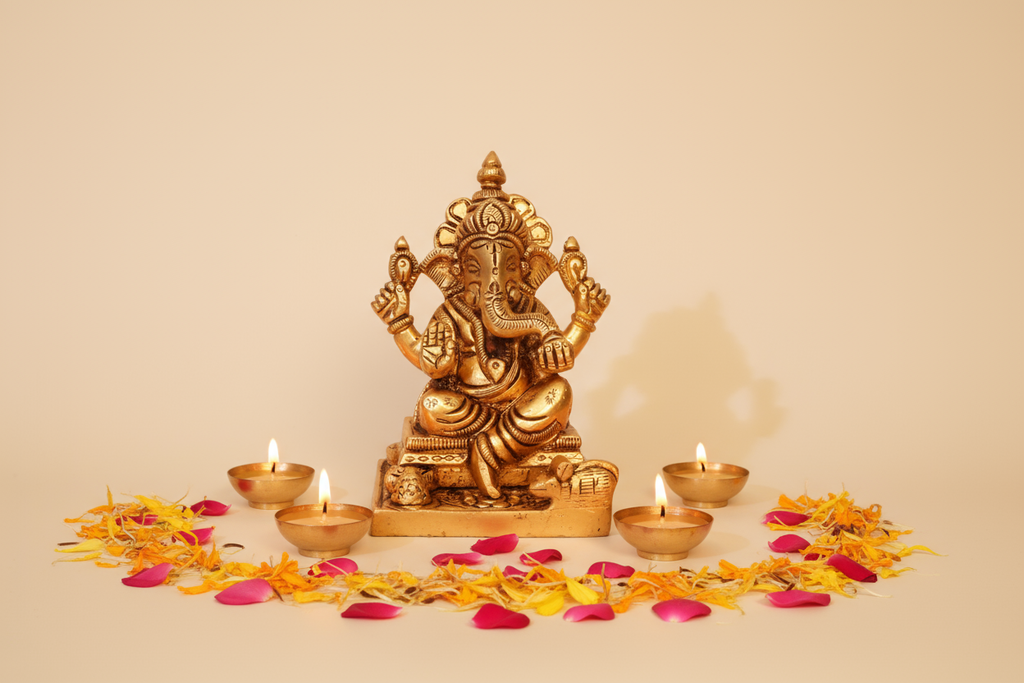 Brass Ganesh with tea lights and marigold petals on warm background